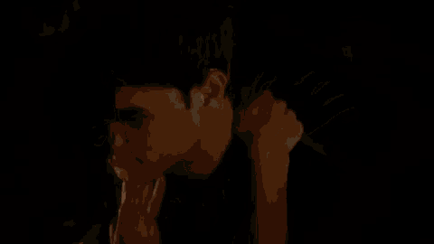 a man and a woman are kissing in the dark and the woman is holding the man 's shoulder .