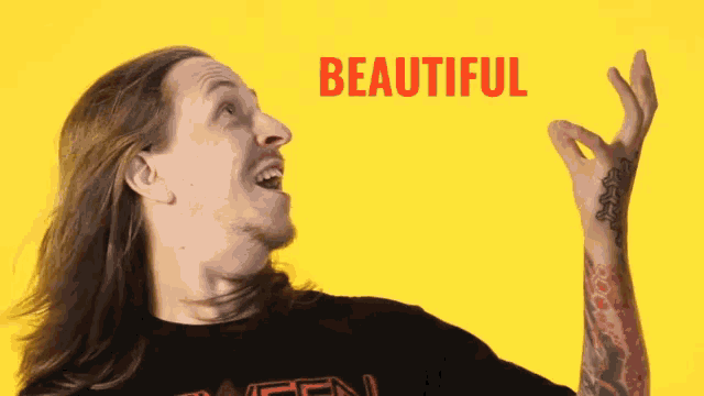 a man with long hair and a black shirt with the word beautiful written in red