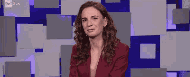 a woman in a red jacket stands in front of a rai 2 hd background