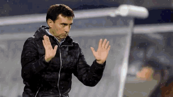 a man in a black jacket waves his hands in the rain