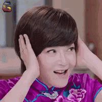 a woman wearing a purple dress is covering her ears with her hands .