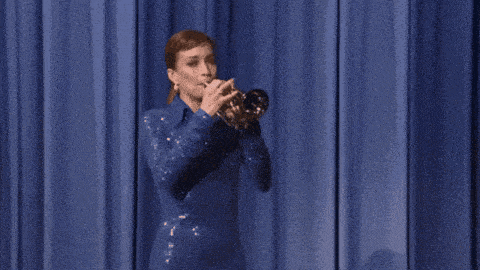 a woman in a blue dress is blowing a trumpet