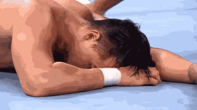 a man laying on a blue mat with his head in his hands