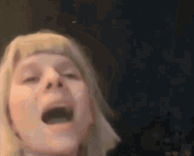 a blurry picture of a person 's face with their eyes closed and a black background .