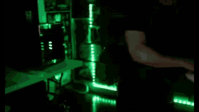 a person is standing in a dark room with green lights on the wall .