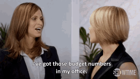two women are talking in an office and one of them says i 've got those budget numbers in my office .