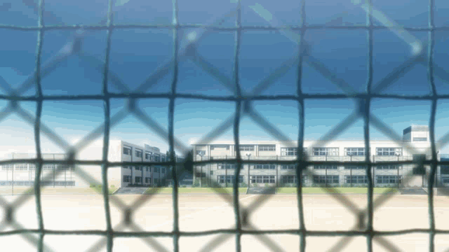 a school behind a chain link fence with a blue sky