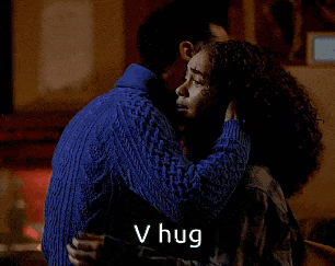 a woman in a blue sweater is hugging another woman in a black shirt