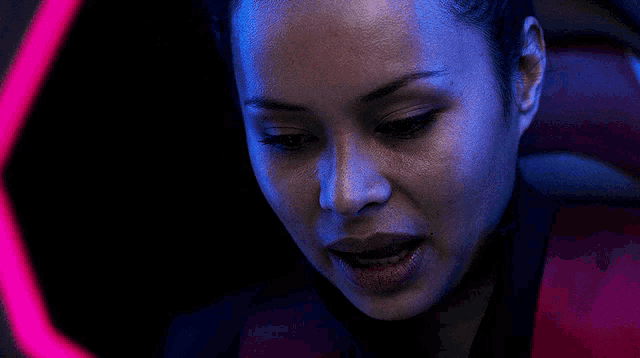 a woman with her eyes closed looks down at something