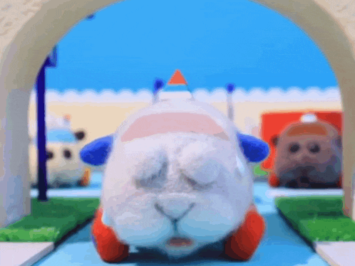 a stuffed animal is driving down a road with its eyes closed and a triangle on its head .