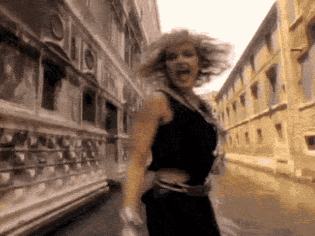 a woman in a black dress is dancing in a street
