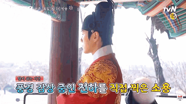 a man in a red and gold costume is standing in front of a building with chinese writing .