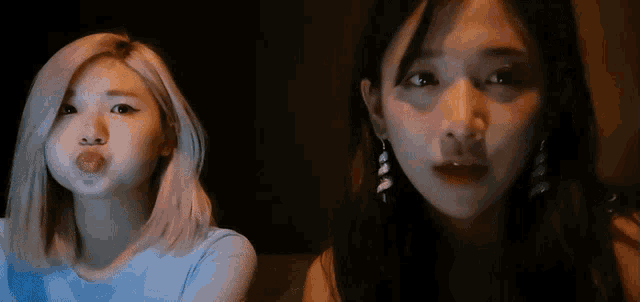 two women are making funny faces in a dark room .