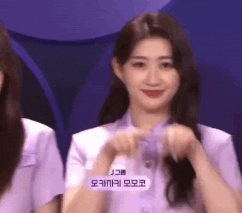a woman in a purple shirt is making a funny face while standing next to another woman .
