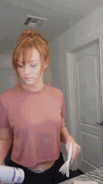 a woman with red hair is holding a spray bottle and a piece of paper
