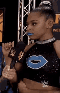 a woman in a cheerleading outfit is talking into a microphone while wearing a wwe wristband