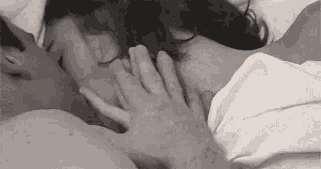 a man is touching a woman 's neck in a bed .