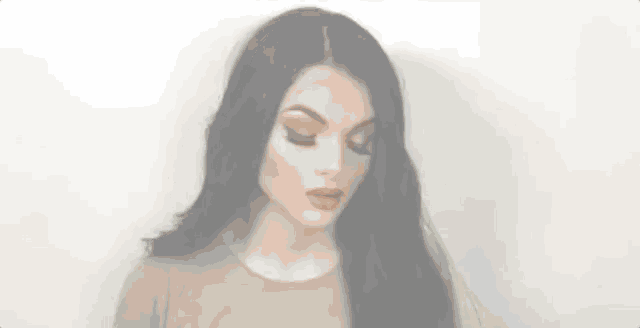 a woman with long black hair is wearing a brown shirt and making a face .