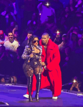 a man in a red coat stands next to a woman singing into a microphone on a stage