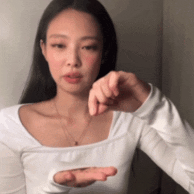a woman wearing a white shirt and a necklace is holding her hand out .