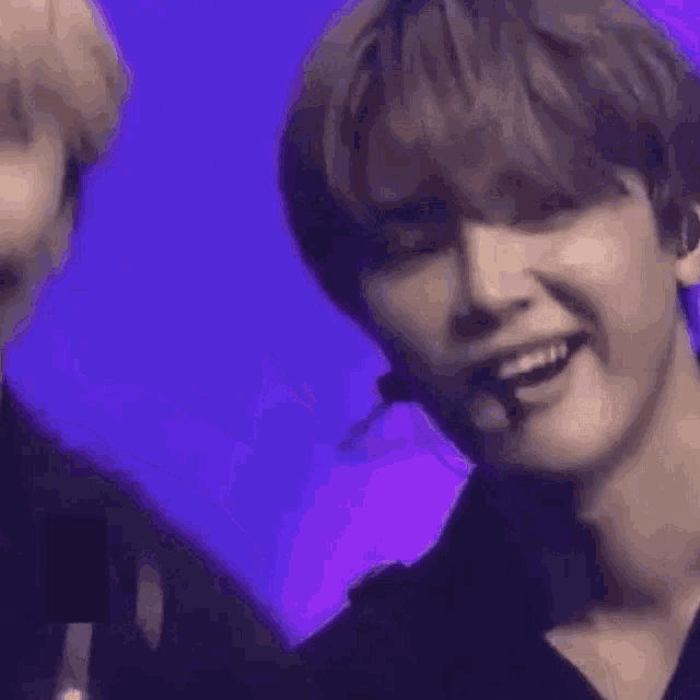 a man and a woman are standing next to each other in front of a purple background and smiling .