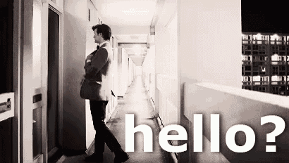 a man in a suit and tie is walking down a hallway and says `` hello ? ''