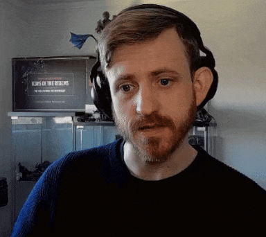 a man with a beard wearing headphones in front of a tv that says icons of the realms