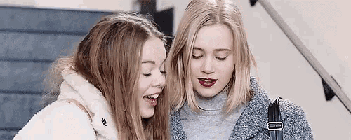 two young women are standing next to each other on the stairs .