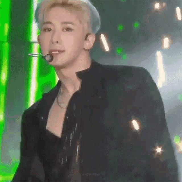 a man is standing on a stage with a microphone in his mouth and a green background .