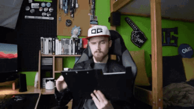 a man wearing a hat that says og looks at a tablet