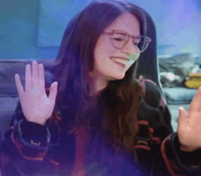a woman wearing glasses is smiling and giving a high five