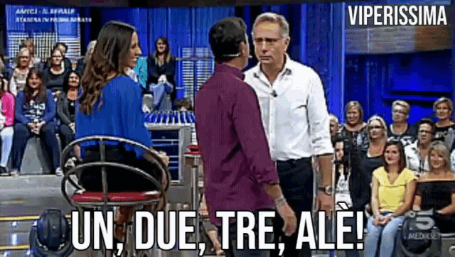 a man and a woman are standing next to each other in front of a crowd with the words un due tre ale written on the bottom