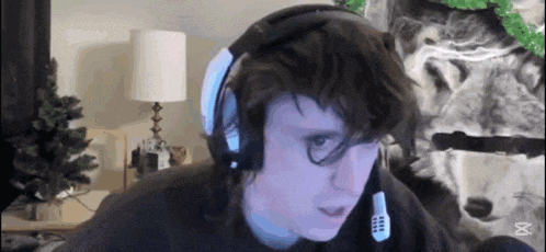 a man wearing headphones is sitting in front of a computer screen .