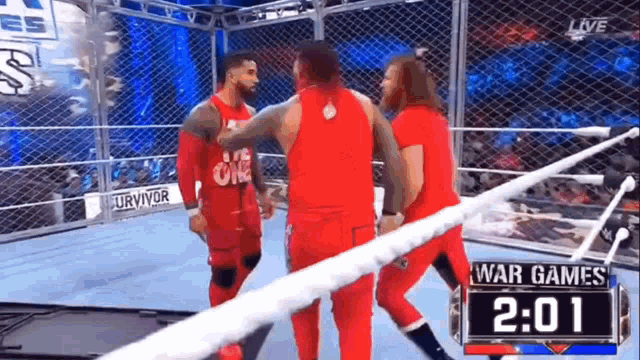 a group of wrestlers are standing in a wrestling ring talking to each other .