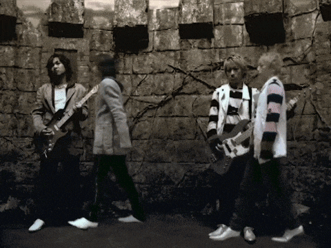 a group of people are standing in front of a stone wall