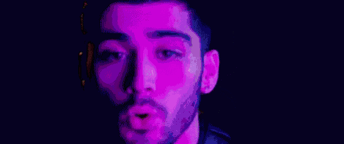 a blurry picture of a man 's face with purple and blue lights coming out of it .