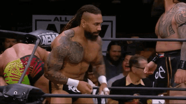 a man in a wrestling ring with a sign that says all elite wrestling on it