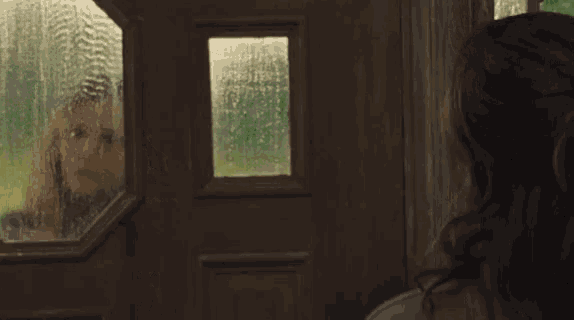 a woman is looking out of a window at a field with trees .