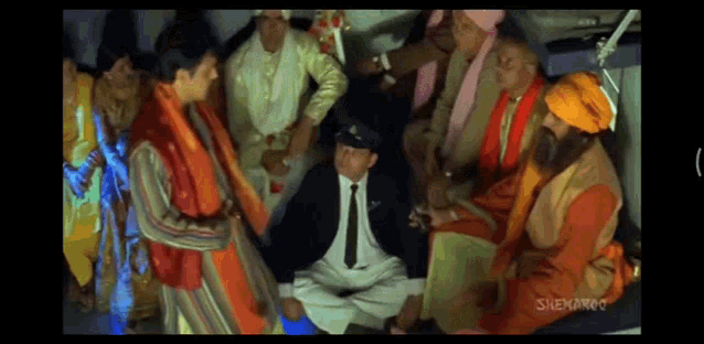 a group of people are sitting around a man in a suit and tie ..