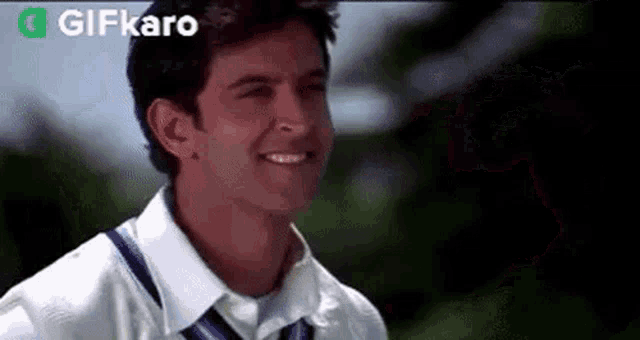 a man wearing a white shirt and tie is smiling .
