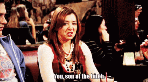 a woman is sitting at a table with a drink and says you son of the bitch