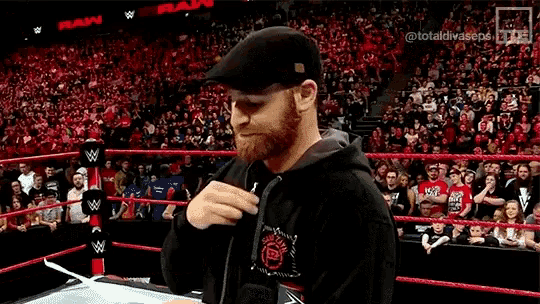 a man is standing in a wrestling ring with a crowd watching .
