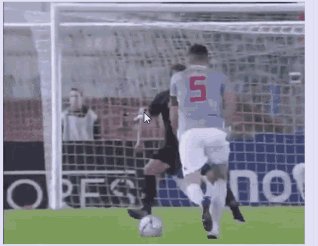 a soccer player with the number 5 on his jersey is kicking a ball
