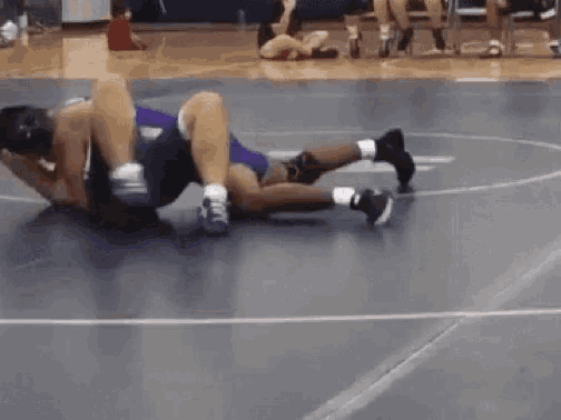 two men are wrestling on a wrestling mat .
