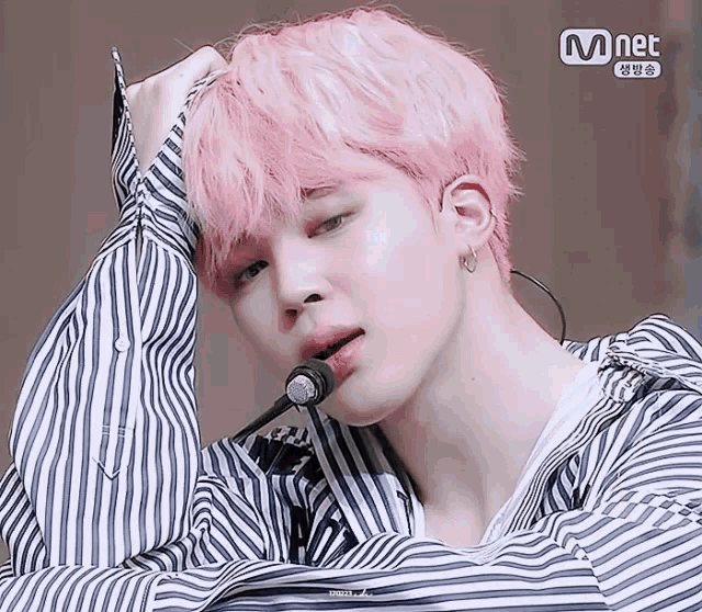 a man with pink hair is wearing a striped shirt and a microphone