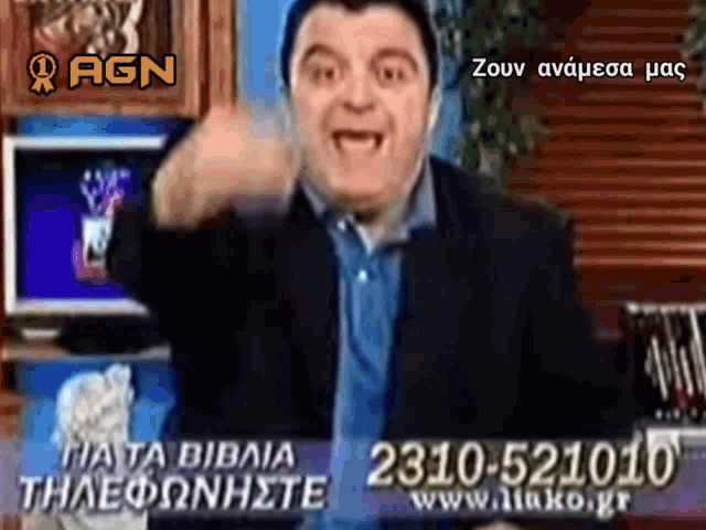 a man giving a thumbs up in front of a sign that says agn on it