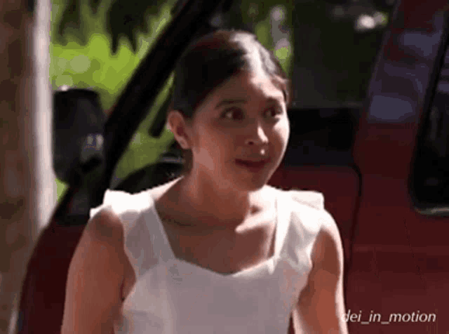 a woman in a white tank top is standing in front of a red van