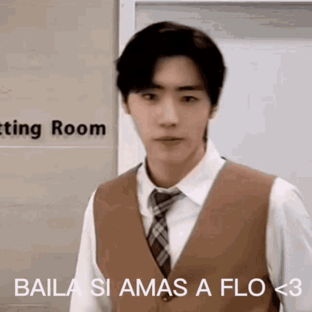 a man in a suit and tie is standing in front of a door and making a funny face .