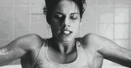 a woman is taking a bath in a bathtub with her eyes closed .