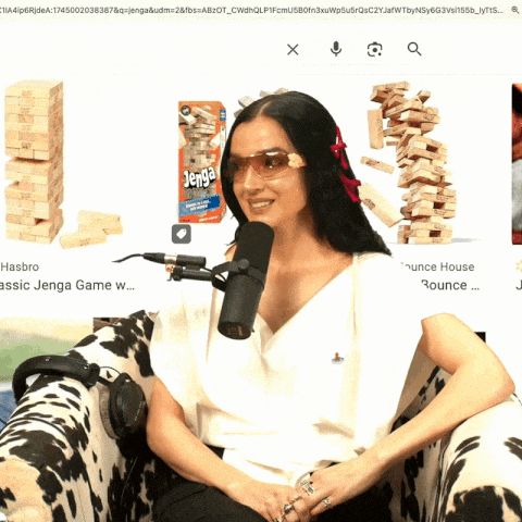 a woman wearing sunglasses is sitting in front of a microphone with jenga blocks in the background